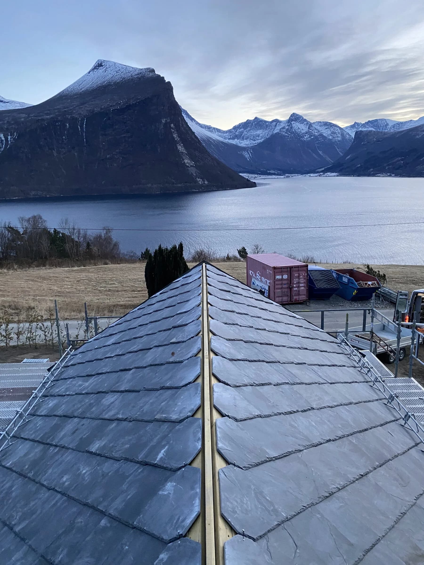 Hytte med skifertak ved fjorden og fjellandskap
