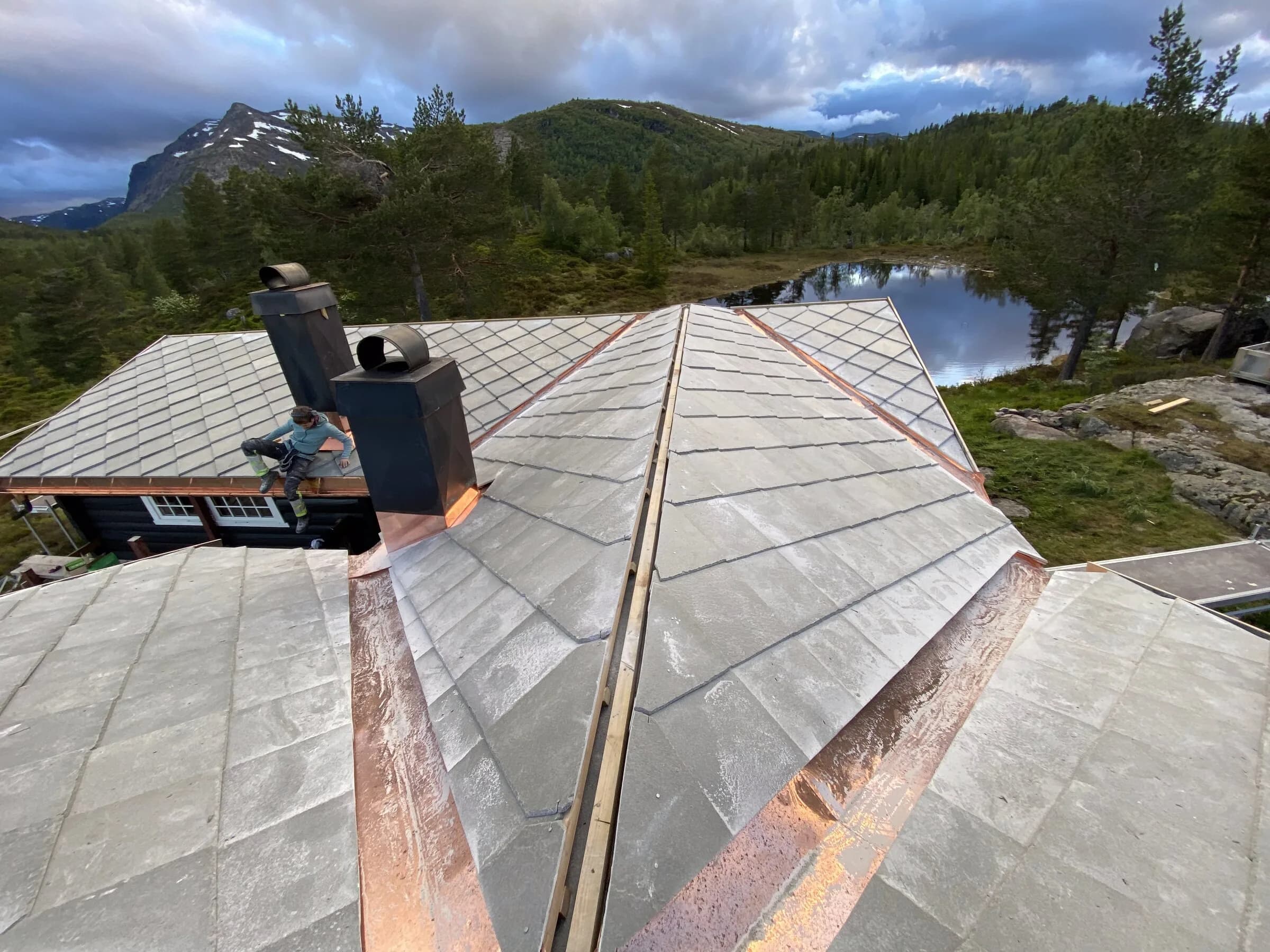 Skifertak og pipe med utsikt mot innsjø