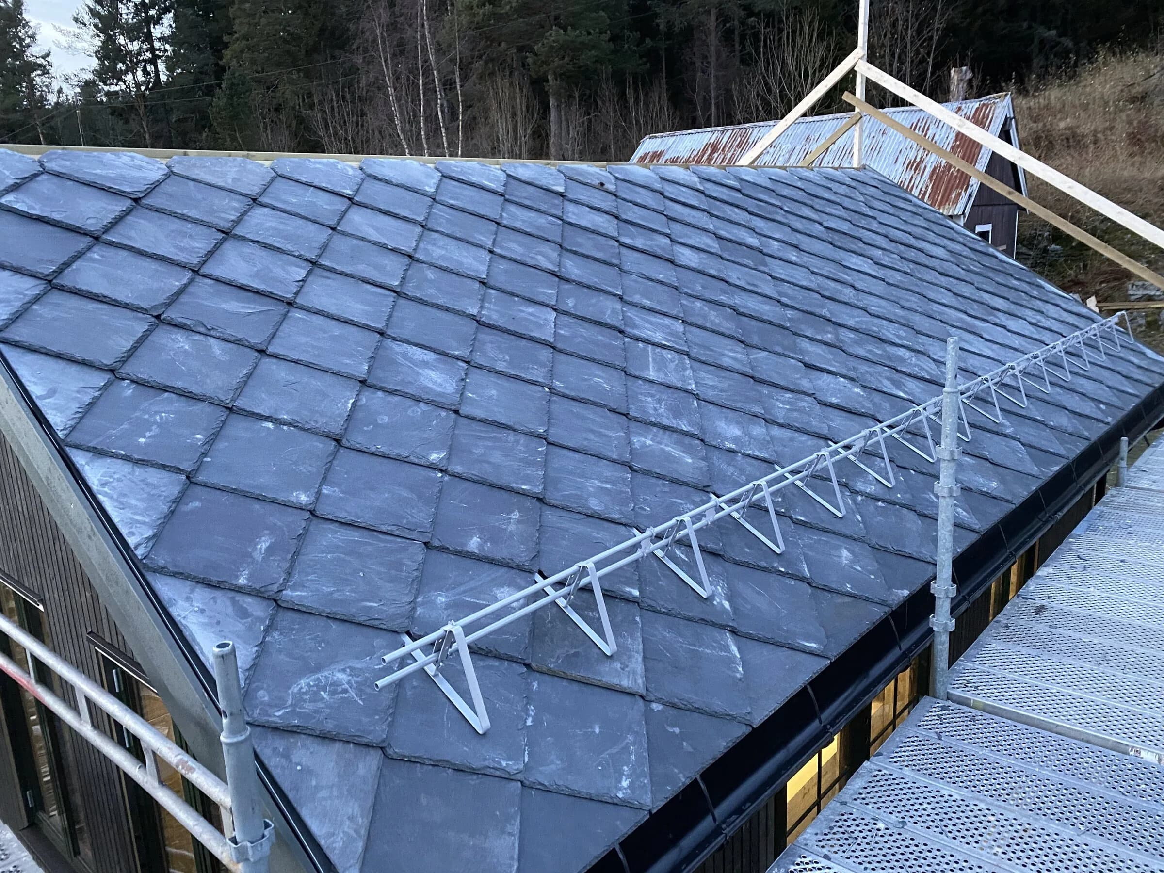 Skifertak med takvinduer og piper under dramatisk skyhimmel