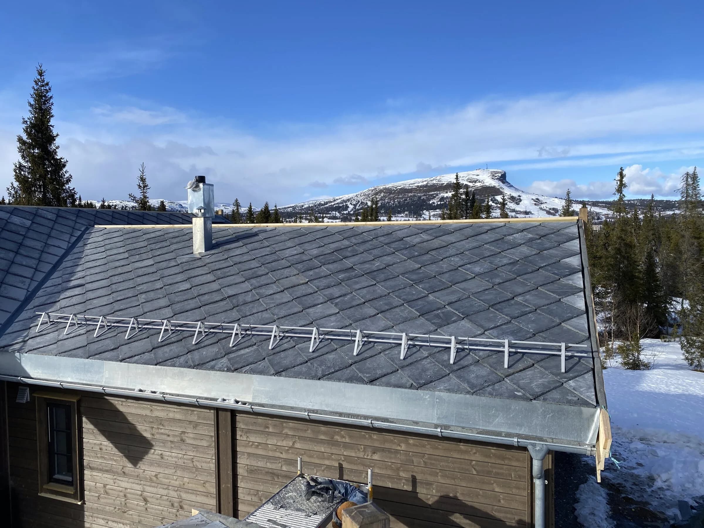 Skifertak på hytte i fjellet med snøflekker