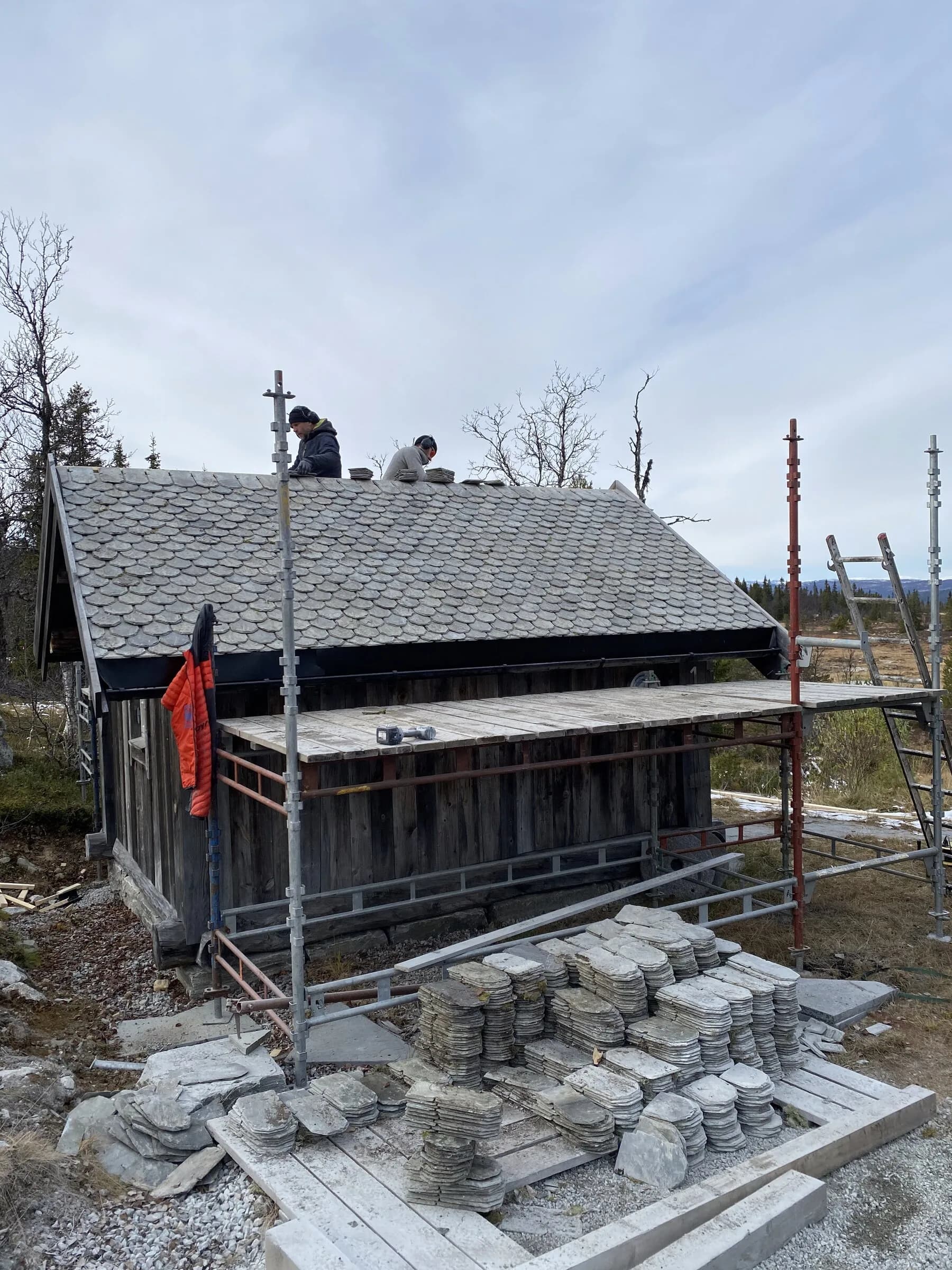 Skiferlegger i arbeid på eldre tømmerbygning