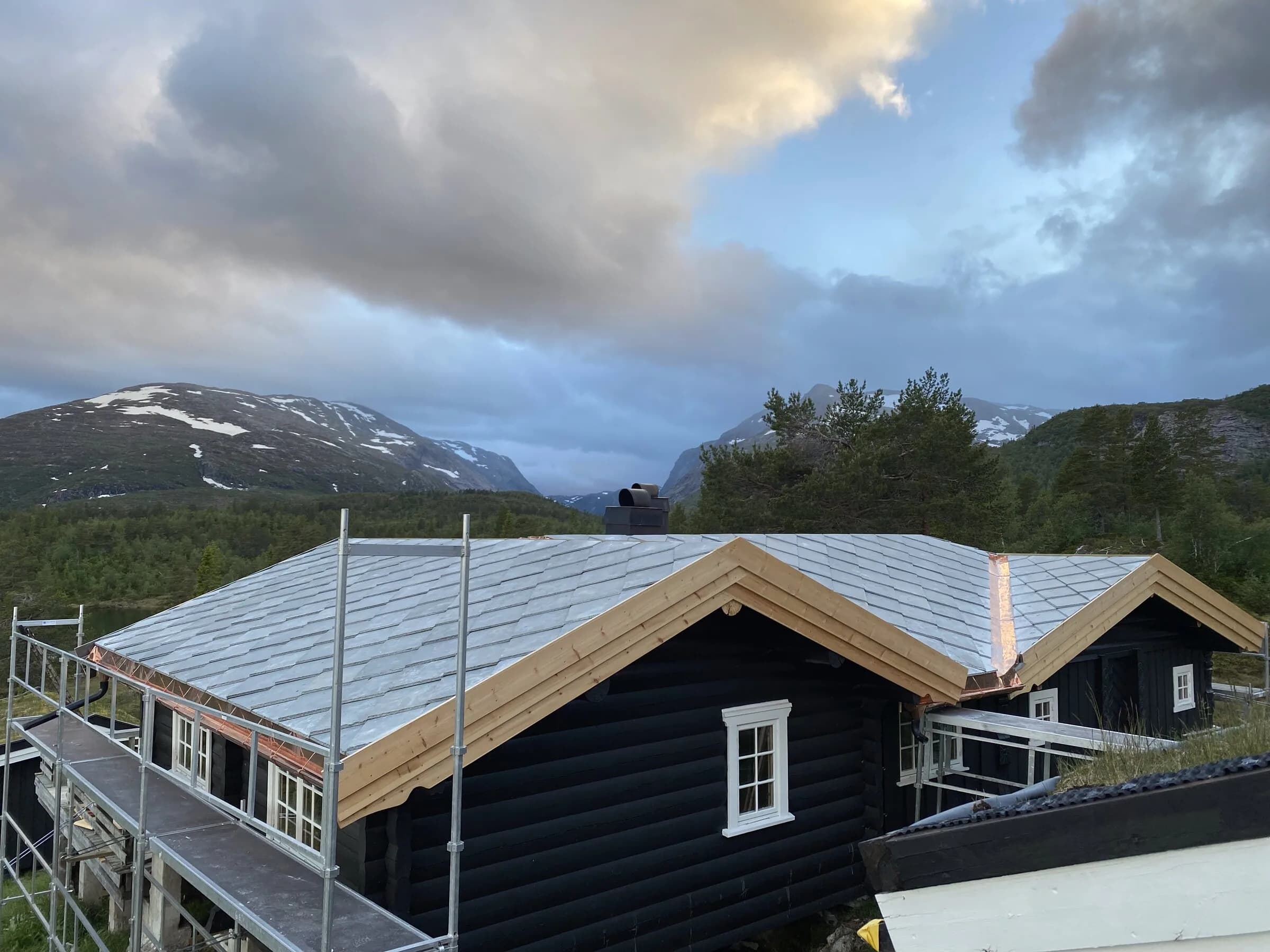 Skifertak i blåtimen med fjellsilhuett